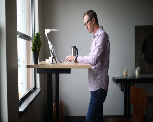Person stretching arms at a desk near a window